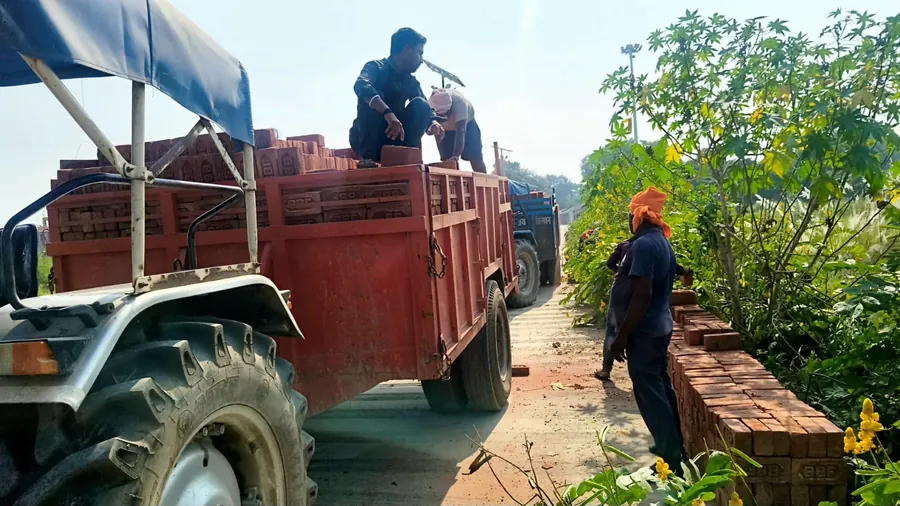 Bricks being unloaded from tractor trolleys at the hostel site